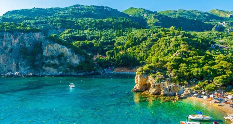 Baie d'un bleu turquoise cristallin, bateaux et falaises luxuriantes le long du littoral verdoyant de Corfou.