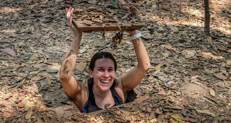 Person emerging from an underground tunnel with a cover lifted above