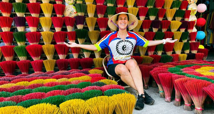 Woman sitting with colorful bundles of incense sticks in the background