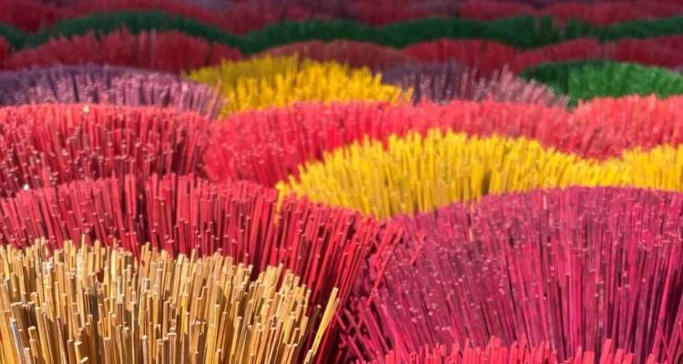 Levendige bundels gekleurde wierookstokjes netjes gerangschikt in dichte rijen rood, geel, roze en groen.