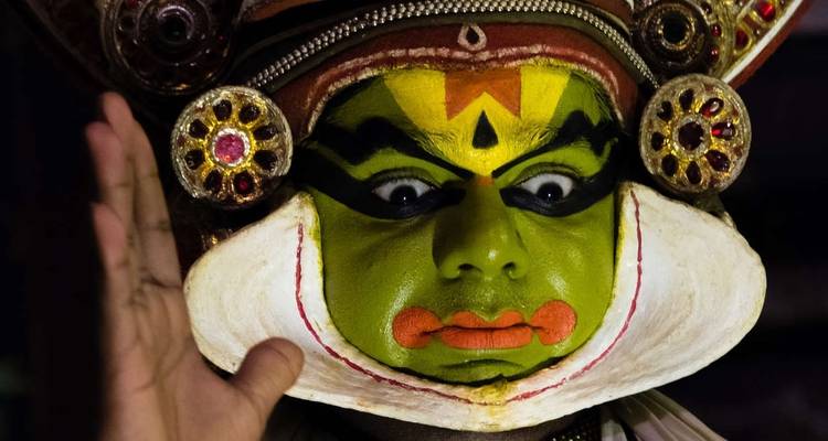 A person wearing traditional colorful makeup and attire during a cultural performance.