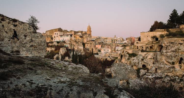 Historical town built into the rocky hillside during dusk.