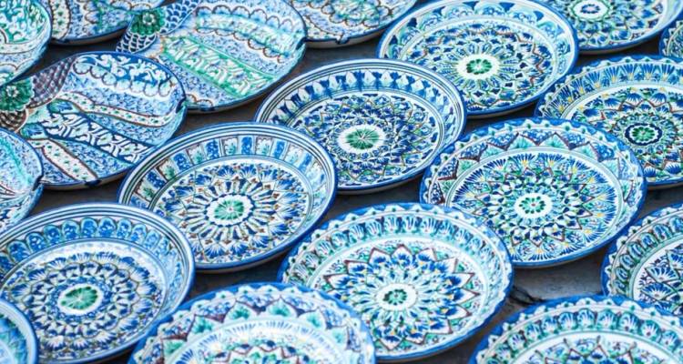 Kunstvoll gemusterte blau-weiße Keramikteller, die in ordentlichen Reihen auf einem usbekischen Kunsthandwerksmarkt ausgestellt sind.