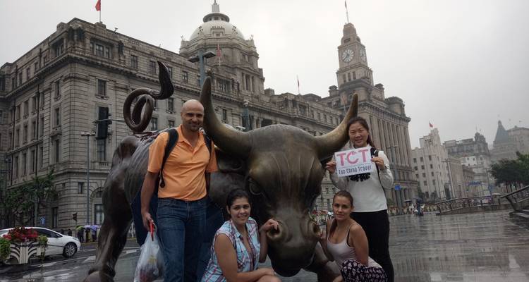 Turistas posando con la estatua del Toro Embistiendo en una plaza de la ciudad.