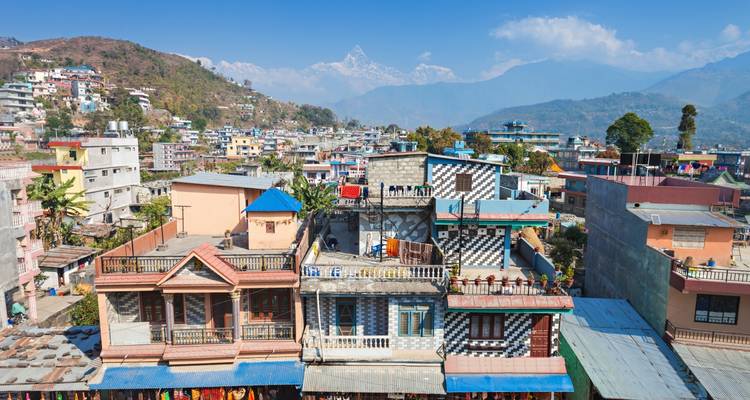 Stadsgezicht met kleurrijke gebouwen en bergen in de verte.
