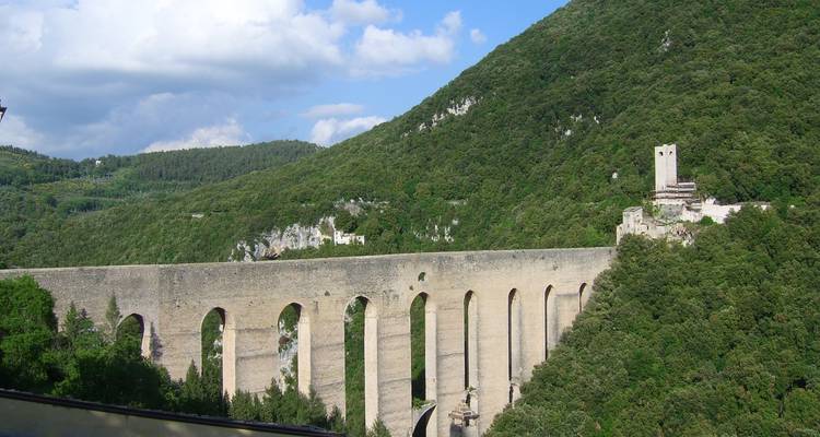 Stenen aquaduct over een groene vallei en heuvels.