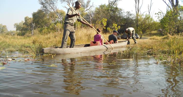 Personas en una barca tradicional de madera en un paisaje fluvial.