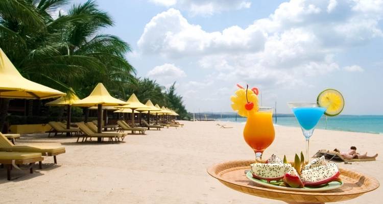 Montaje de playa tropical con bandeja de bebidas y comida.