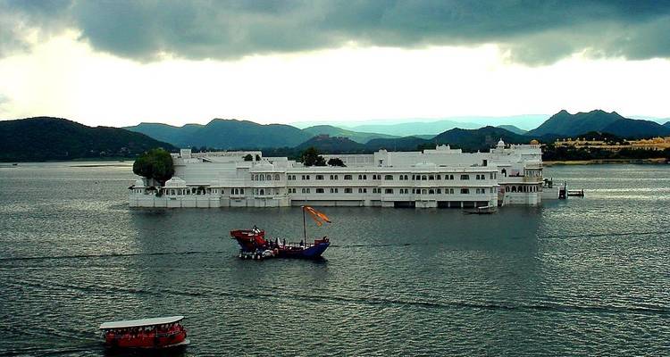 A white palace seemingly floating on a lake with boats around it.