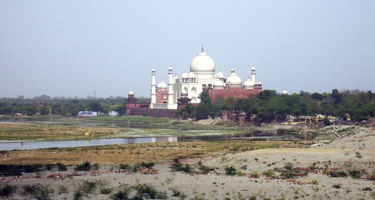 Fernblick auf das Taj Mahal über einen Fluss hinweg.