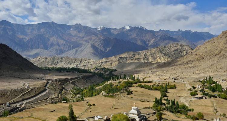 Mountain valley with green fields and small village.