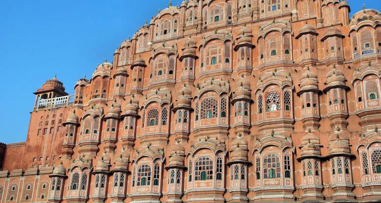 Hawa Mahal's ornate facade with detailed windows under a blue sky.