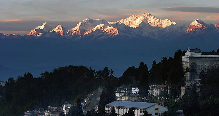 Majestueuses montagnes enneigées avec un village en contrebas lors d'un lever de soleil.
