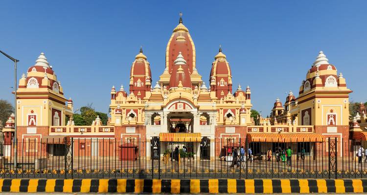 De rode en crèmekleurige torenspitsen van Delhi's Laxminarayan (Birla) Tempel steken af tegen een wolkeloze blauwe hemel.
