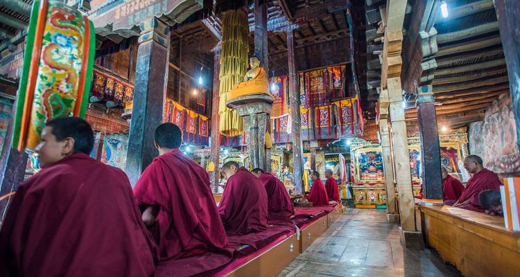 Des moines priant à l'intérieur d'un temple décoré avec des tapisseries colorées.