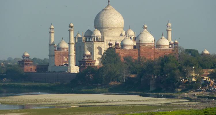 Zijaanzicht van de Taj Mahal gelegen nabij een kalme rivier.