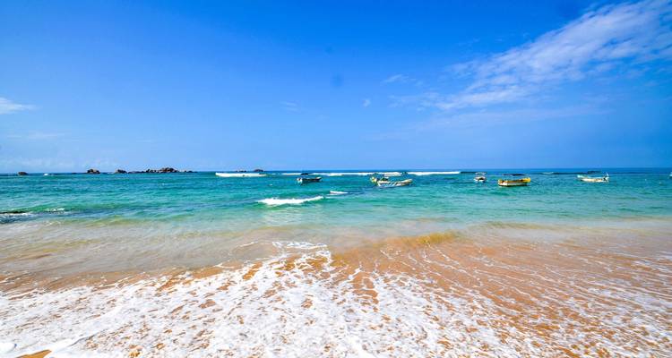 A serene beach scene with boats and a clear blue sky.