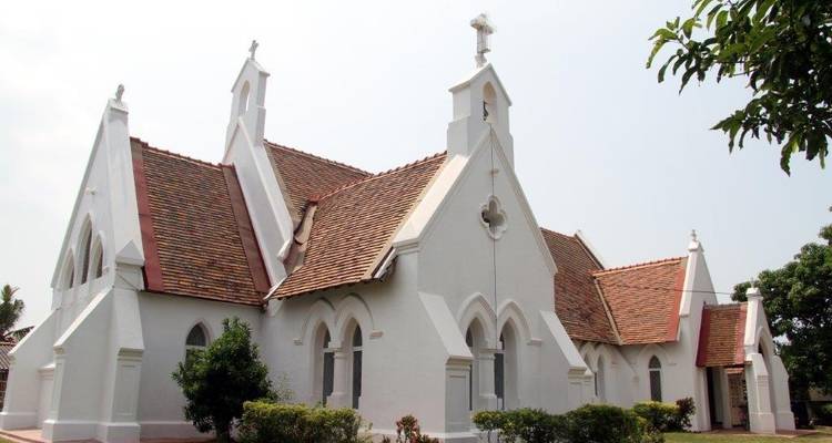 White church building with red-tile roof surrounded by greenery.