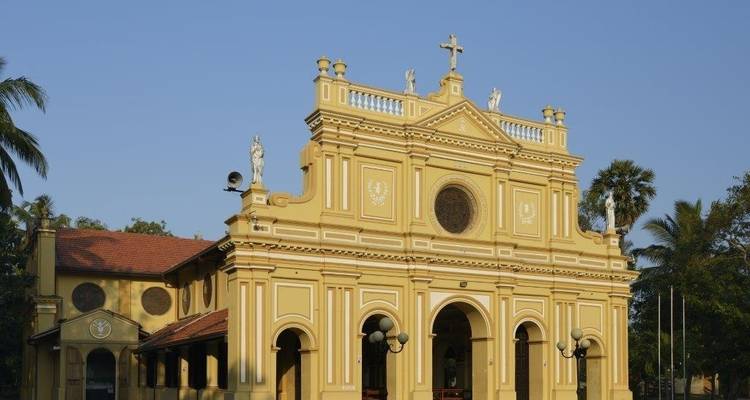 Historical church building with a yellow facade and statues.