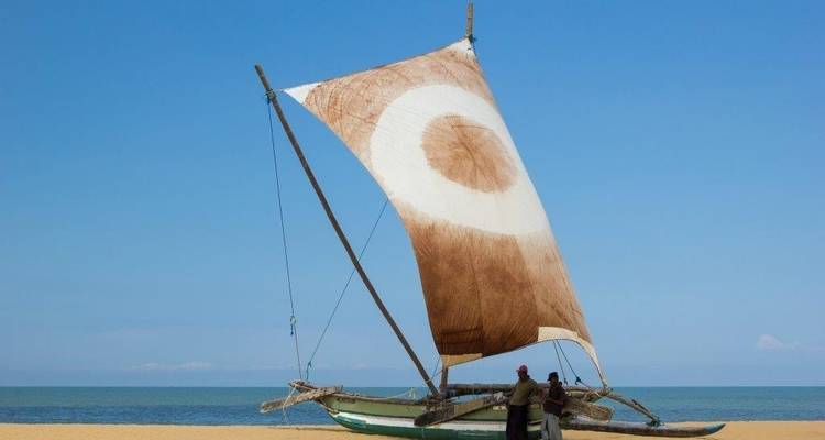 Traditional sailboat with a unique circular sail on the beach.