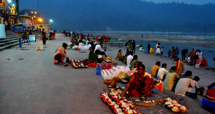 Marché au bord de la rivière avec des gens et des offrandes de fleurs.