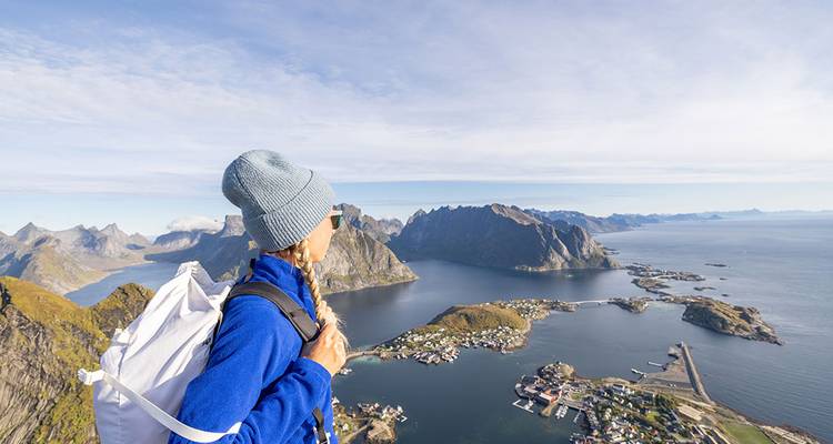 A person standing at a mountain viewpoint overlooking islands and sea.
