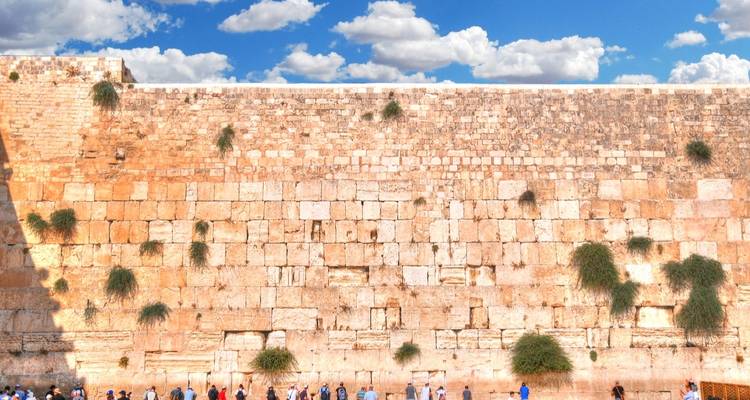 Visitantes cerca del Muro de los Lamentos en un entorno de ciudad histórica.