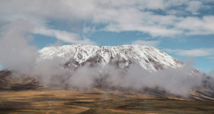 Schneebedeckter Berg, teilweise von Wolken verdeckt.