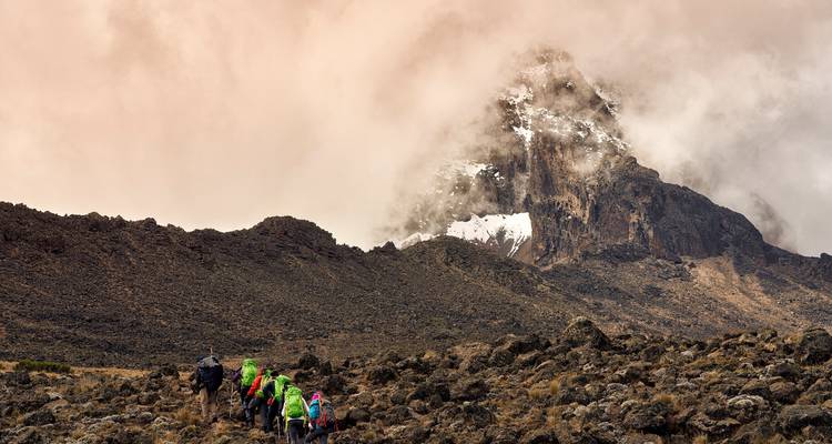 Gruppe von Wanderern, die sich einem nebelverhüllten Gipfel in Tansania nähern.