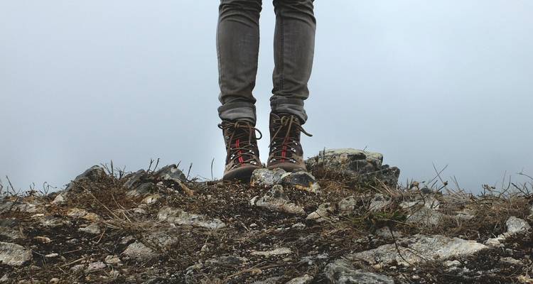 Nahaufnahme von Stiefeln, die auf felsigem Boden stehen.