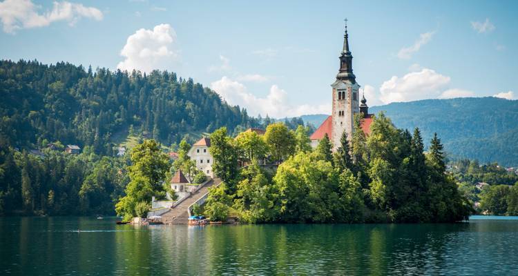 Icónica Iglesia de la Asunción en la Isla de Bled rodeada de un lago de cristal y montañas boscosas