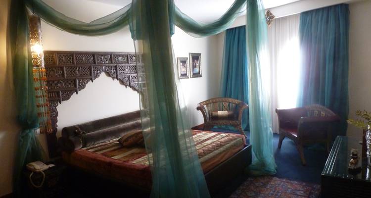 Elegantly decorated room with a four-post bed and drapes.