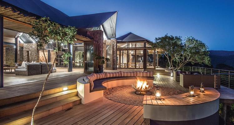 Luxury lodge with fire pit and panoramic open architecture at twilight.