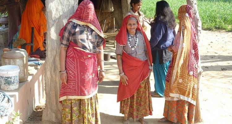 Frauen in traditioneller indischer Kleidung stehen draußen.