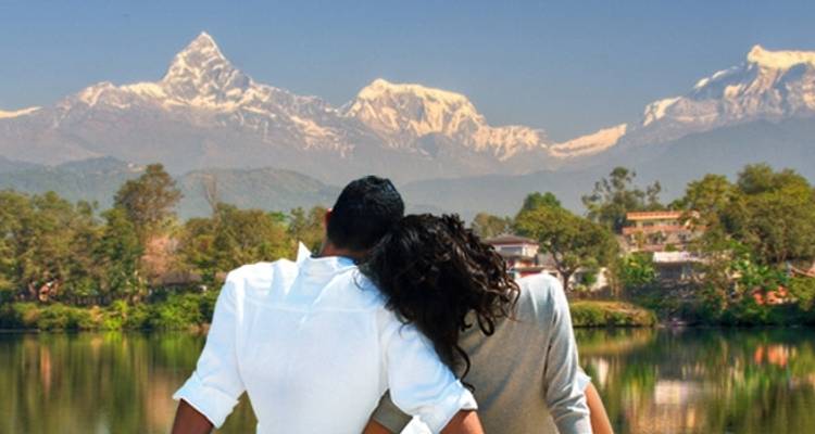 Paar sitzt an einem See mit Bergblick.