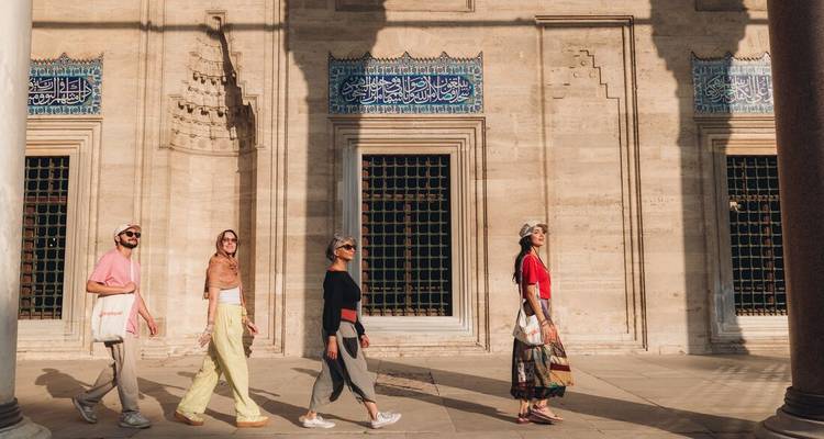 Group of people walking in line past a historic building.
