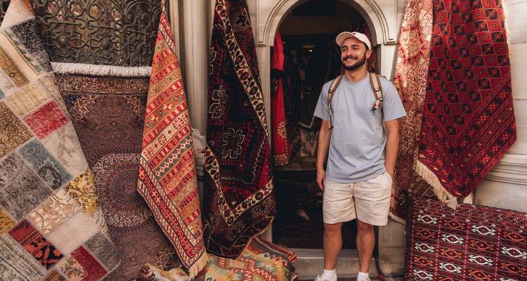 Man standing at the entrance to a shop selling traditional rugs.