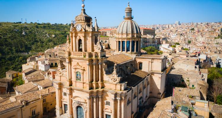 La impresionante Catedral Barroca de San Giorgio se eleva sobre los techos de tejas de Ragusa Ibla bajo la brillante luz de la mañana.
