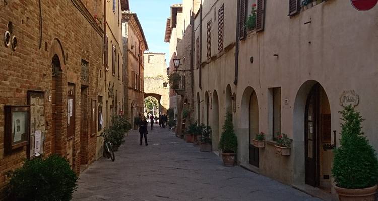 Une rue étroite dans un village italien avec des gens qui marchent.