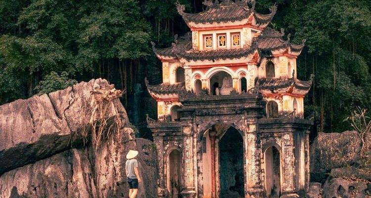 Personne debout près d'un temple traditionnel enchâssé dans les rochers.