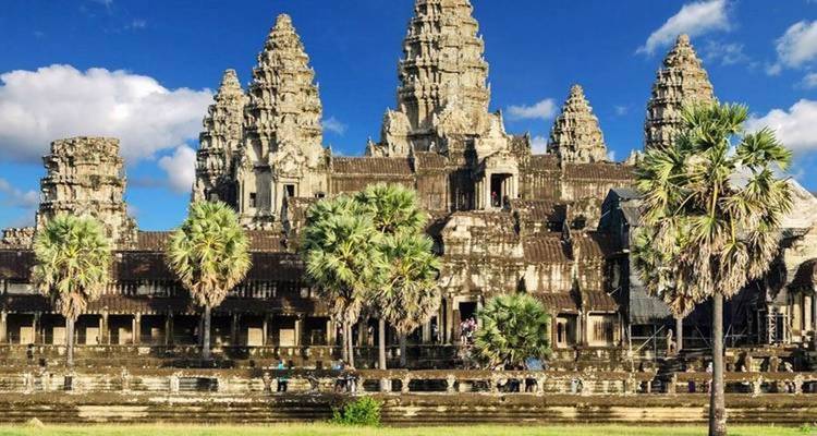 Templo de Angkor Wat con reflejo en el agua y palmeras.