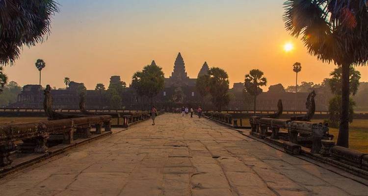 Angkor Wat al amanecer con algunos turistas caminando.