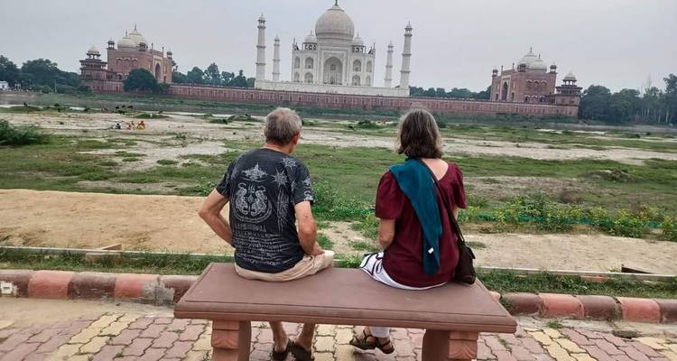 Deux personnes assises sur un banc face au Taj Mahal.