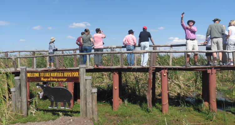 Touristen betrachten den Hippo-Pool des Manyara-Sees von einem Holzsteg aus.
