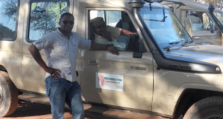 Reiseveranstalter stehen neben einem Safari-Fahrzeug.