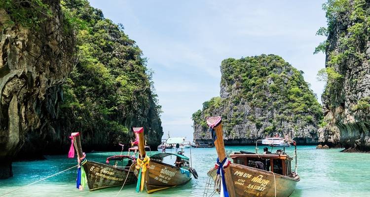 Long-tail boats in a picturesque bay with steep cliffs.