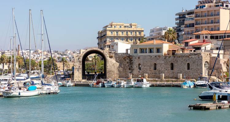 El puerto veneciano de Heraklión con sus tinglados de barcos arqueados y veleros anclados en aguas turquesas.