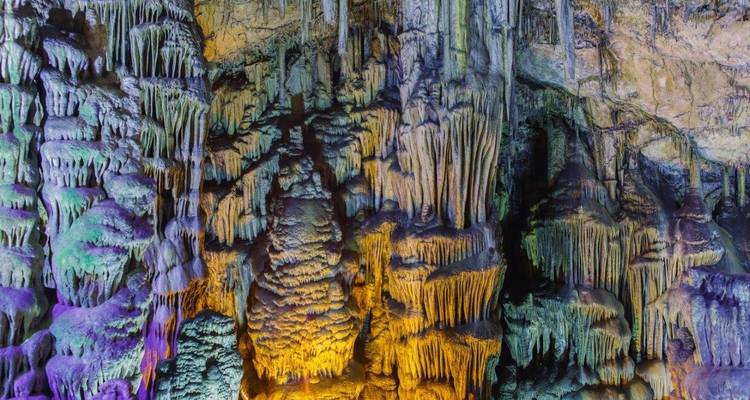 Interior de cueva con formaciones rocosas coloridas y estalactitas.