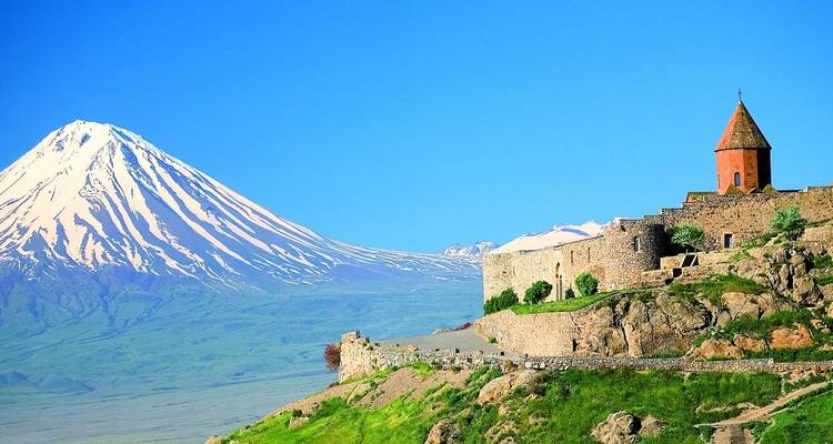 Klooster op een heuvel met een torenhoge besneeuwde bergachtergrond.