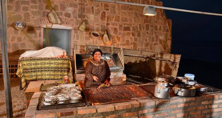 Woman preparing food at a street-side grill at night.